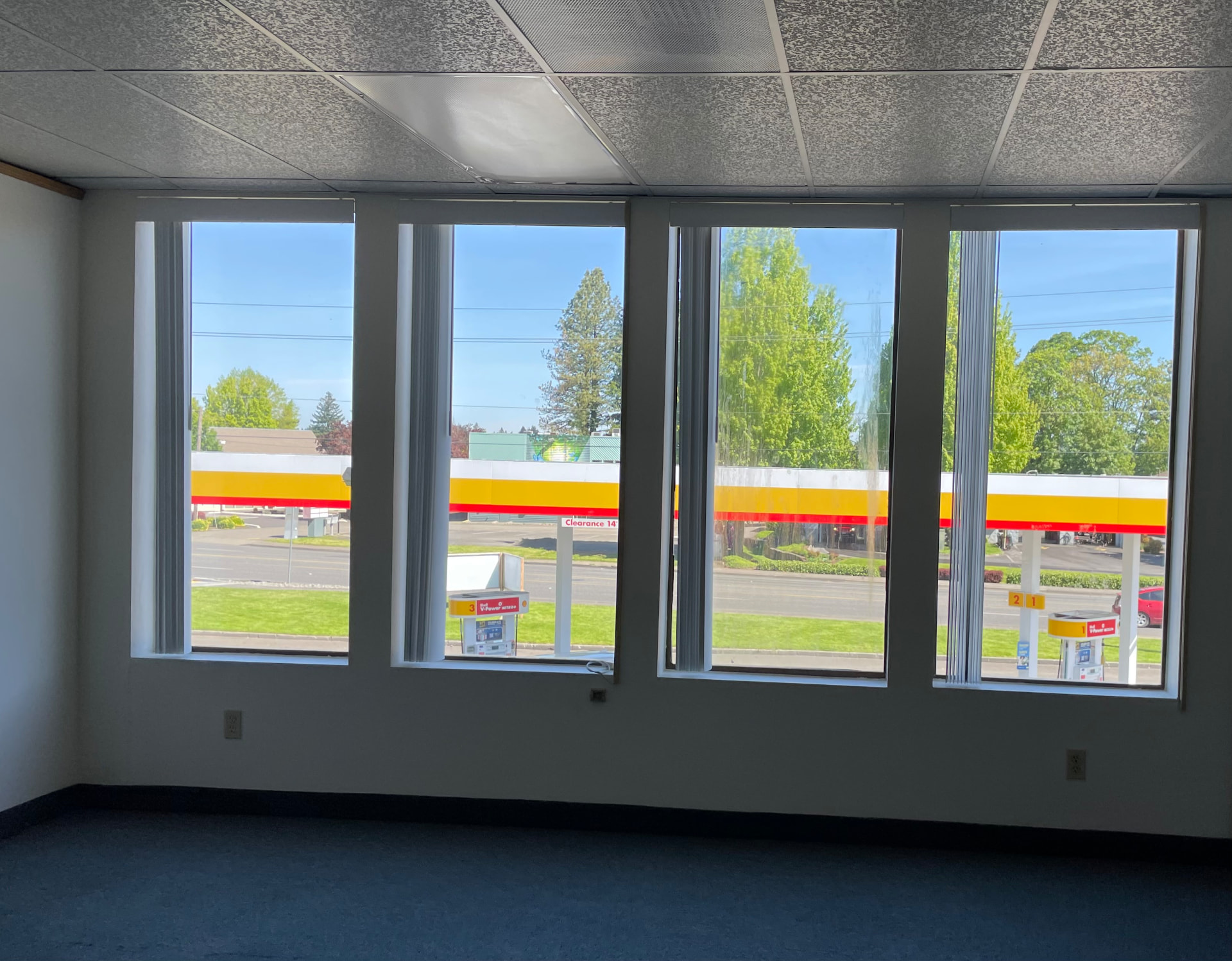 Empty office room with a wall of windows overlooking the gas station below